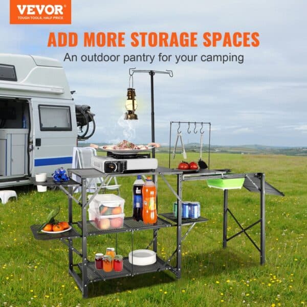 VEVOR camping kitchen table with storage shelves beside a camper, set in a scenic outdoor field.