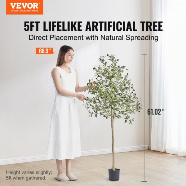 person standing next to 5ft VEVOR artificial olive tree in a minimalist room.