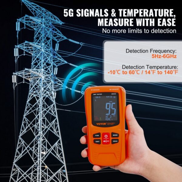 hand holding VEVOR emf meter near power lines, displaying frequency and temperature detection ranges.