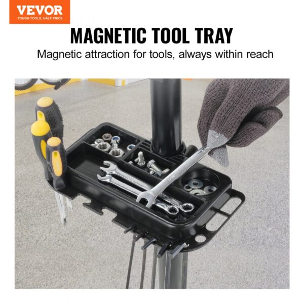 magnetic tool tray on VEVOR bike repair stand holding screws, wrenches, and screwdrivers with gloved hand.